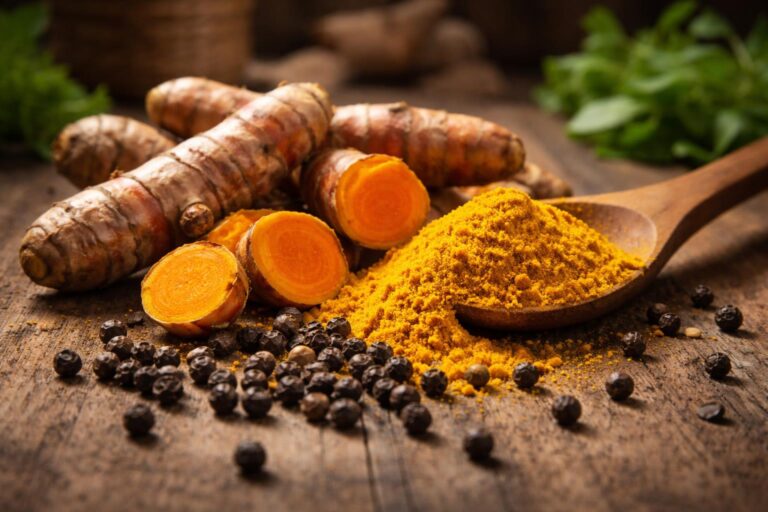 Koření kurkuma a černý pepř na dřevěném stole