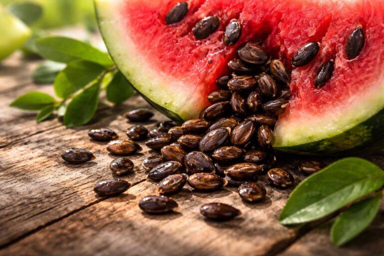 Semínka melounu na dřevěné lžíci v blízkosti čerstvého melounu